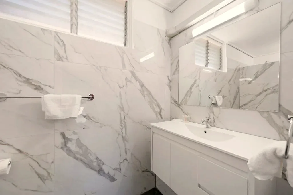 Private marble-tiled bathroom with vanity and large mirror